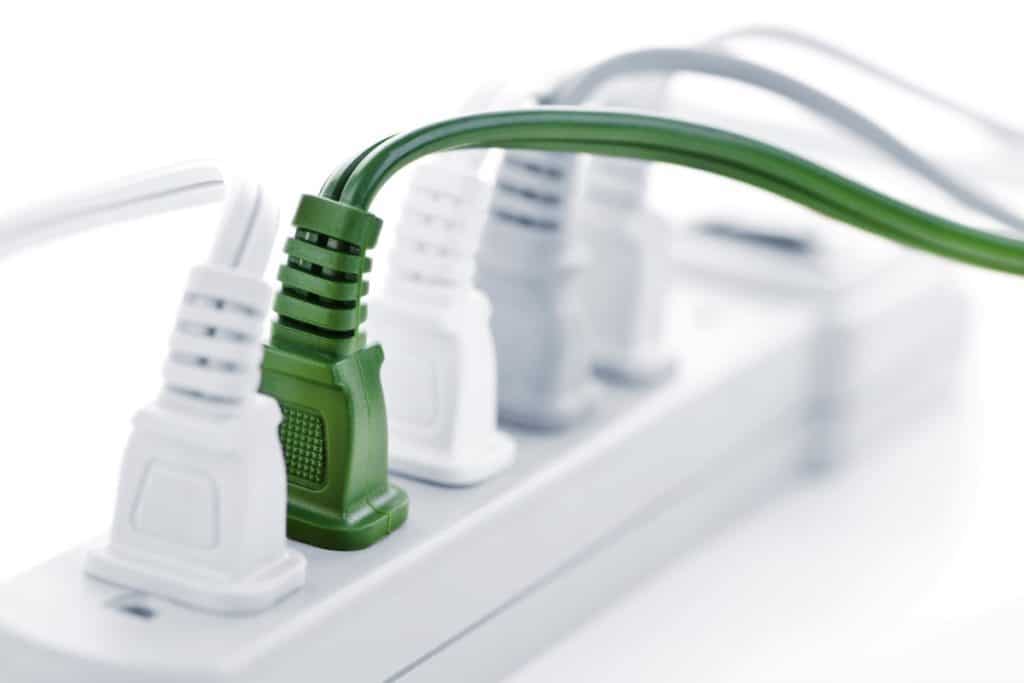A power strip fully loaded with plugs, including a green surge-protected plug