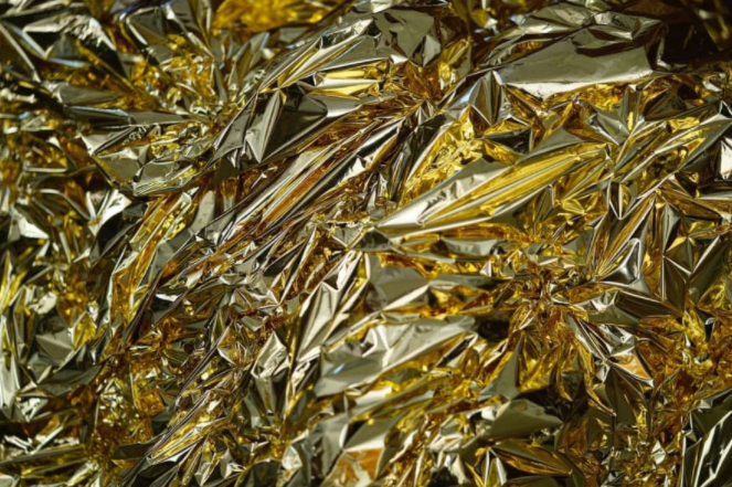Close-up of a crinkled mylar blanket showing its gold and silver reflective sides